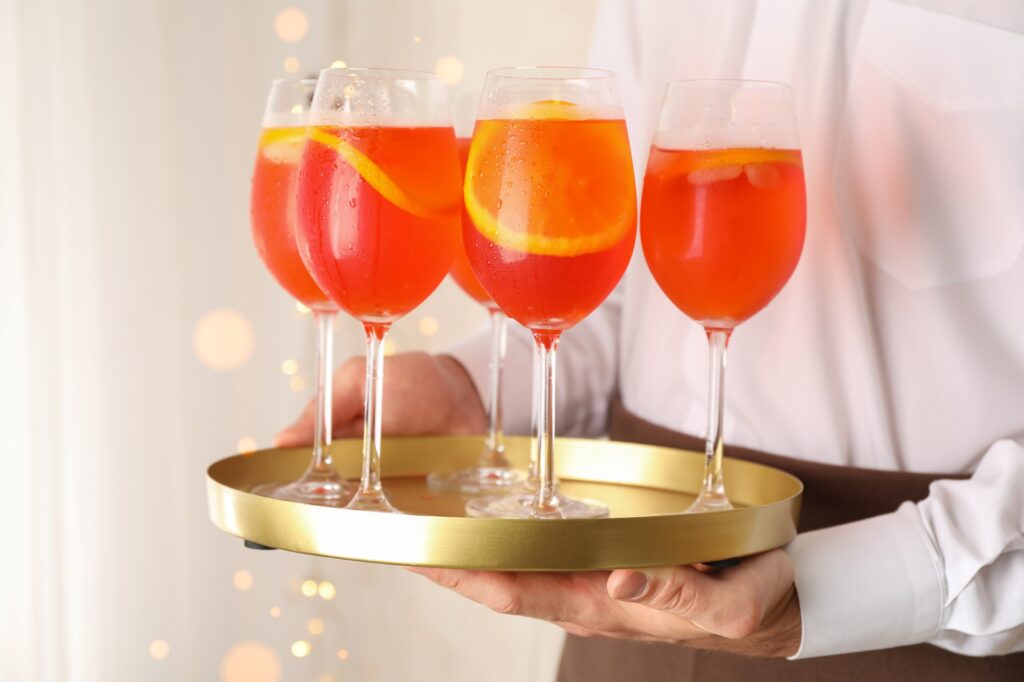 Waiter holding tray with aperol spritz cocktail. Summer drink