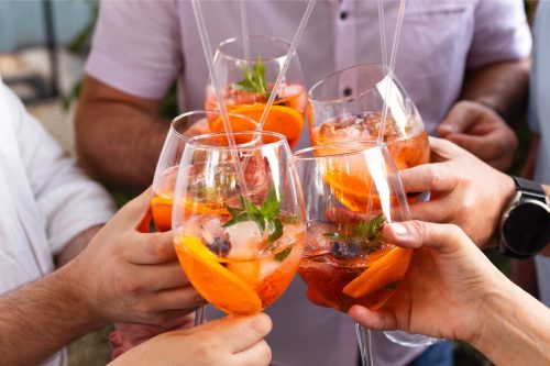 Happy friends spending time together, drinking Aperol spritz cocktail