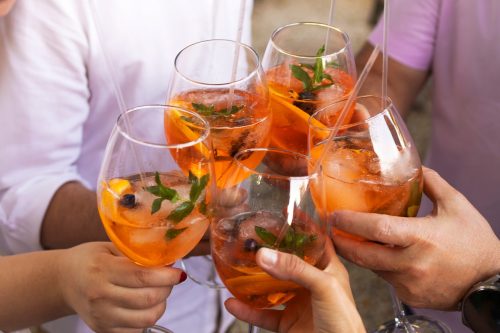Happy friends spending time together, drinking Aperol spritz cocktail