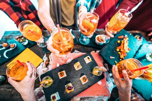 People hands toasting multicolored spritz drinks